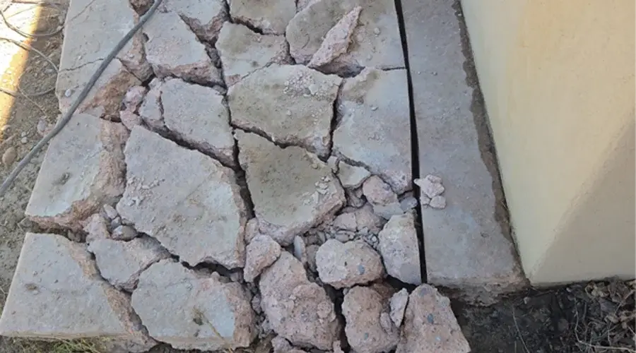 Cracked and broken concrete slab showing damage and debris, illustrating the need for concrete demolition and removal services.