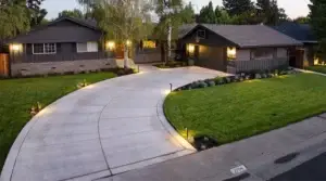Concrete driveway leading to residential homes with landscaped gardens and outdoor lighting in Loomis, CA, showcasing quality landscaping services by Rogers Landscaping.