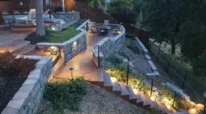 Creative backyard landscape design with stone patio, retaining walls, and outdoor lighting.