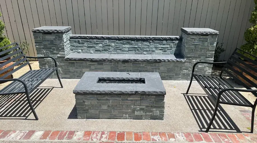 Cozy outdoor seating area featuring a stone fire pit and seat walls, ideal for gatherings and relaxation in a landscaped backyard.