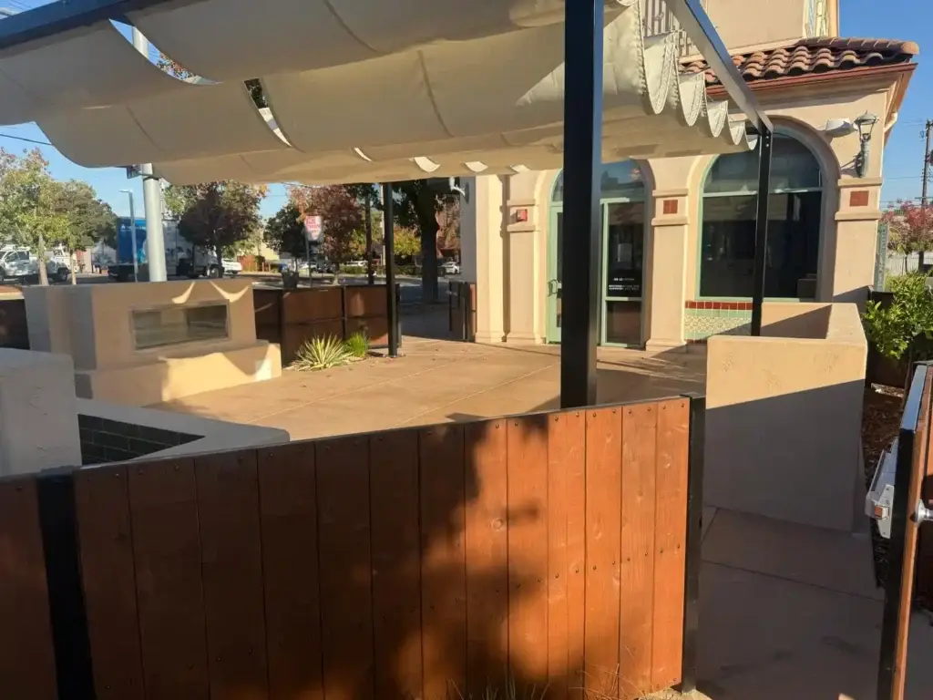 Outdoor dining patio renovation at Hawks Public House featuring modern design elements, shaded seating area, and surrounding landscaping, showcasing Rogers Landscaping's craftsmanship and project execution.