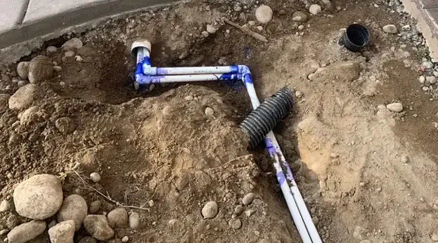 Irrigation system installation featuring PVC pipes and connectors in a landscaped area, illustrating efficient water management for healthy plant growth.