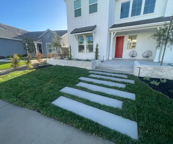 Modern residential landscaping in Carmichael, CA, featuring a stylish front yard with concrete stepping stones, lush green grass, and decorative plants, showcasing expert design and craftsmanship by Rogers Landscape.