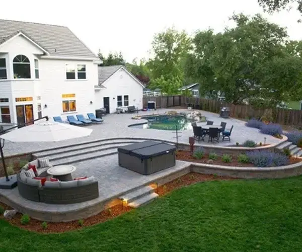 Premium residential landscaping in El Dorado Hills, CA, featuring a beautifully designed outdoor living area with a pool, patio, and lounge seating, showcasing hardscape elements and lush greenery.