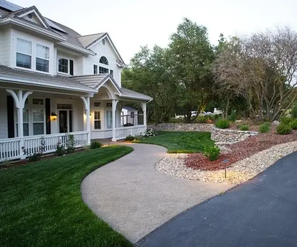 Residential landscaping design featuring a well-maintained lawn, curved concrete pathway, and decorative stone hardscaping, enhancing outdoor aesthetics in Lincoln, CA.