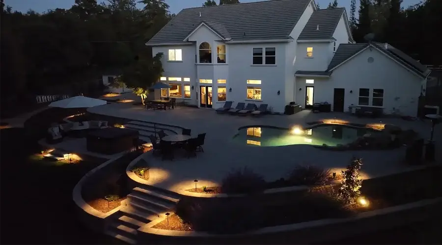 Elegant outdoor lighting illuminating a modern home and pool area at night, showcasing pathways, seating, and landscaping features for enhanced ambiance and safety.