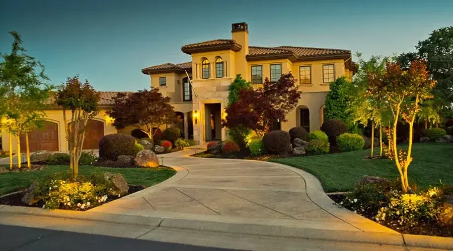 Elegant residential home illuminated by low-voltage landscape lighting, showcasing path lighting along the driveway, accentuating architectural features and surrounding greenery in Loomis, CA.