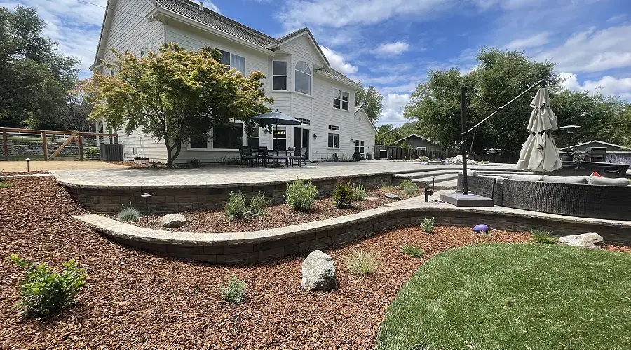 Modern backyard featuring expertly installed mulch beds, decorative rocks, and a spacious patio, enhancing the landscape's aesthetic appeal and functionality.
