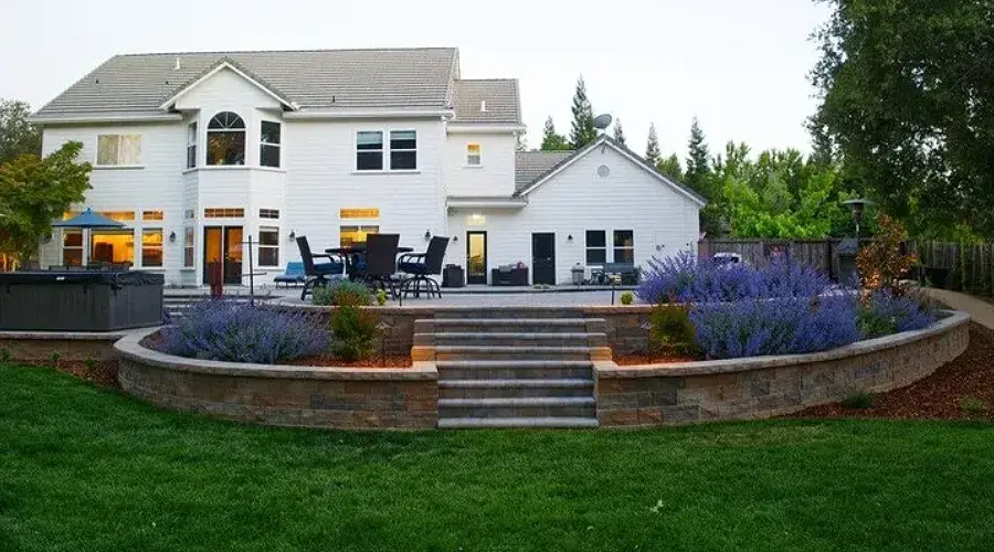 Modern residential landscape in Loomis, CA, featuring a low-maintenance design with artificial grass, stone steps, and vibrant lavender plants, emphasizing sustainable outdoor living.