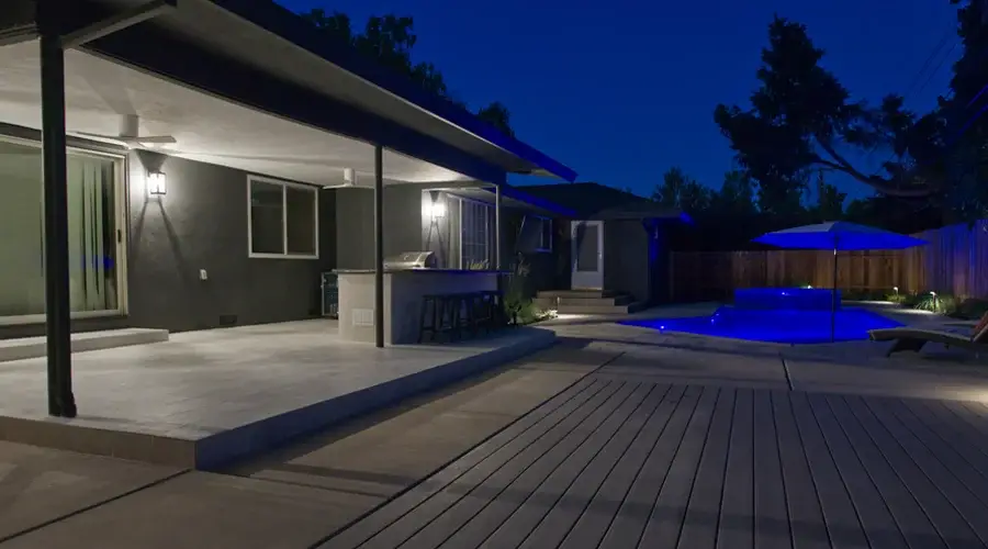 Elegant outdoor bar and dining area with modern design, illuminated at night, adjacent to a swimming pool, showcasing seamless integration of functionality and aesthetics.