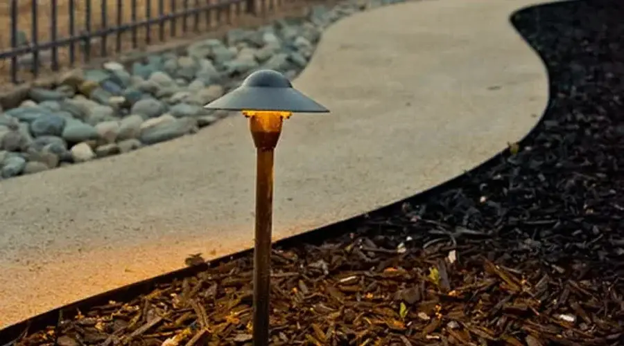 Path lighting fixture illuminating a winding garden path, enhancing outdoor aesthetics and safety in a landscaped setting.