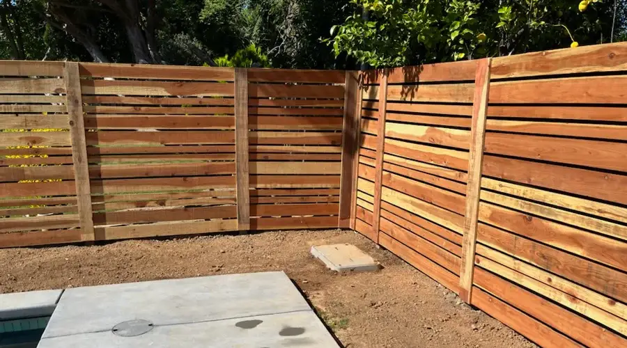 Wooden privacy screen enclosing outdoor shower area, showcasing slatted design and natural finish, enhancing comfort and aesthetics in outdoor living spaces.