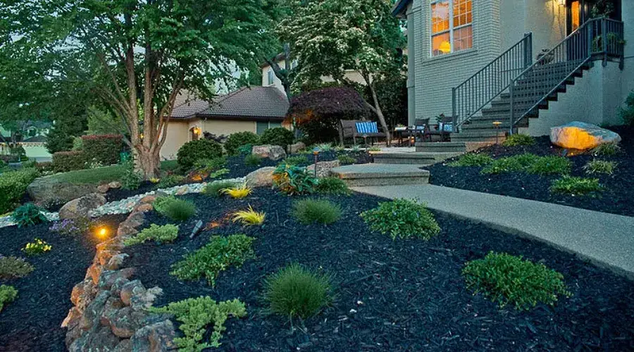 Landscape renovation featuring a well-lit pathway, diverse planting beds, and a welcoming home entrance, showcasing Rogers Landscape's commitment to enhancing outdoor living spaces.