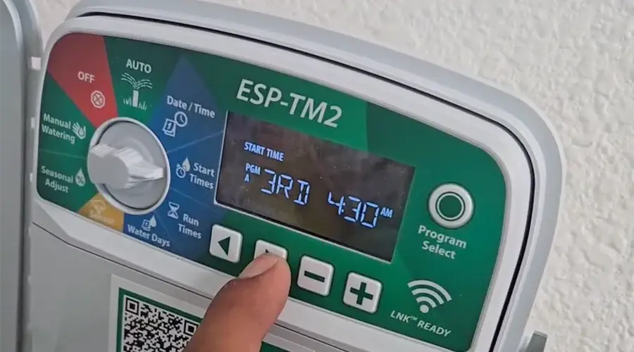 Smart irrigation controller display with user adjusting settings for optimal watering schedule, featuring ESP-TM2 model interface, emphasizing water efficiency and landscape health.