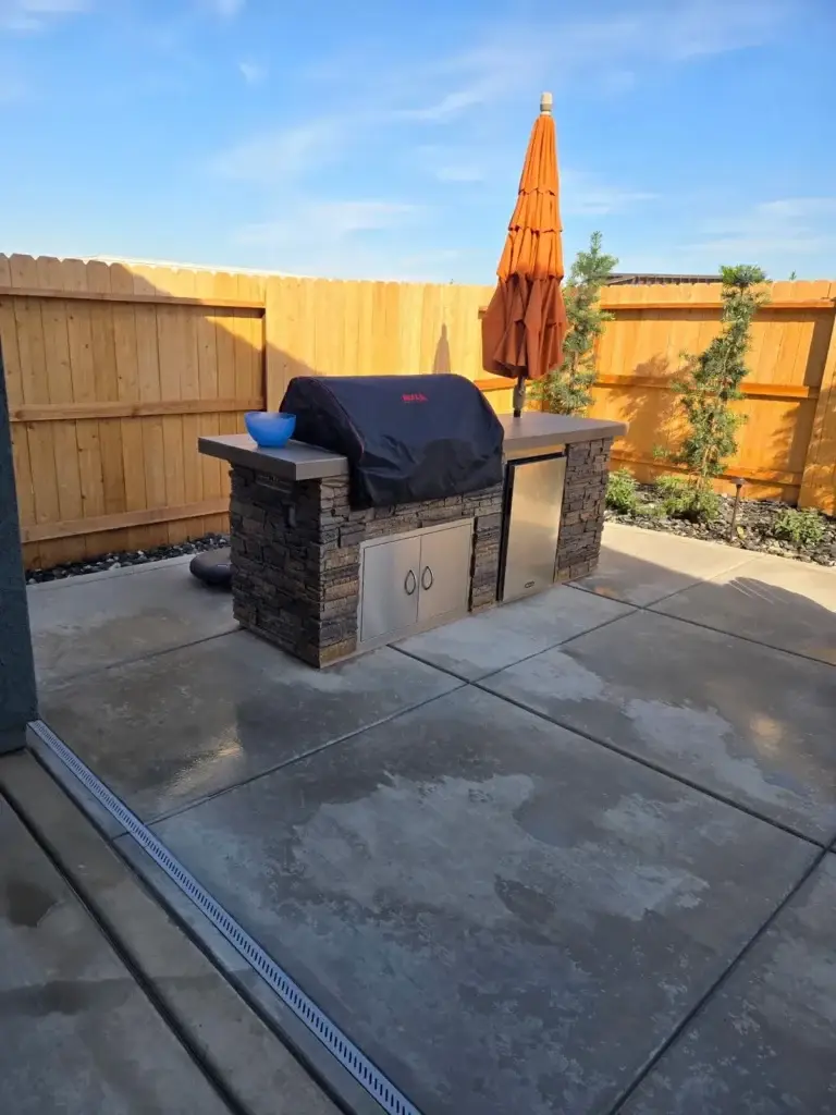 Professional landscape contractor installing a custom outdoor kitchen with modern appliances