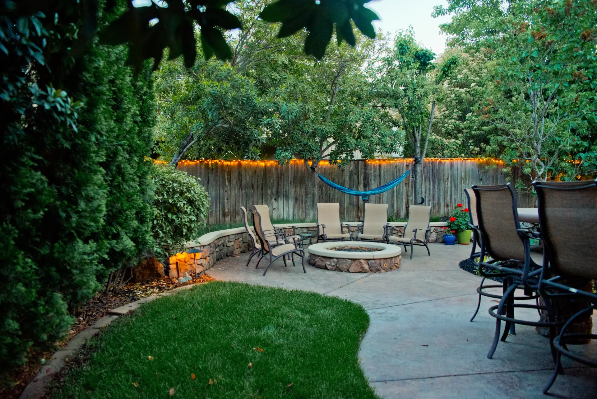 Outdoor living space with fire pit, seating area, and string lights illustrating quality concrete hardscaping.