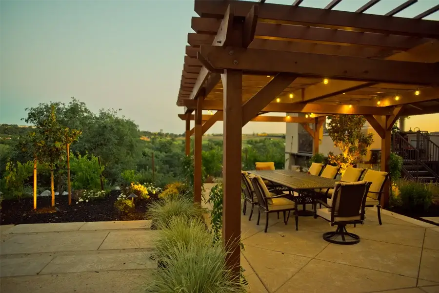 Wooden pergola and patio dining area with string lights, outdoor living space design by Rogers